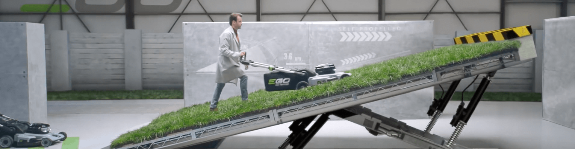 A man in a lab environment testing an EGO Mower on a steep incline. 